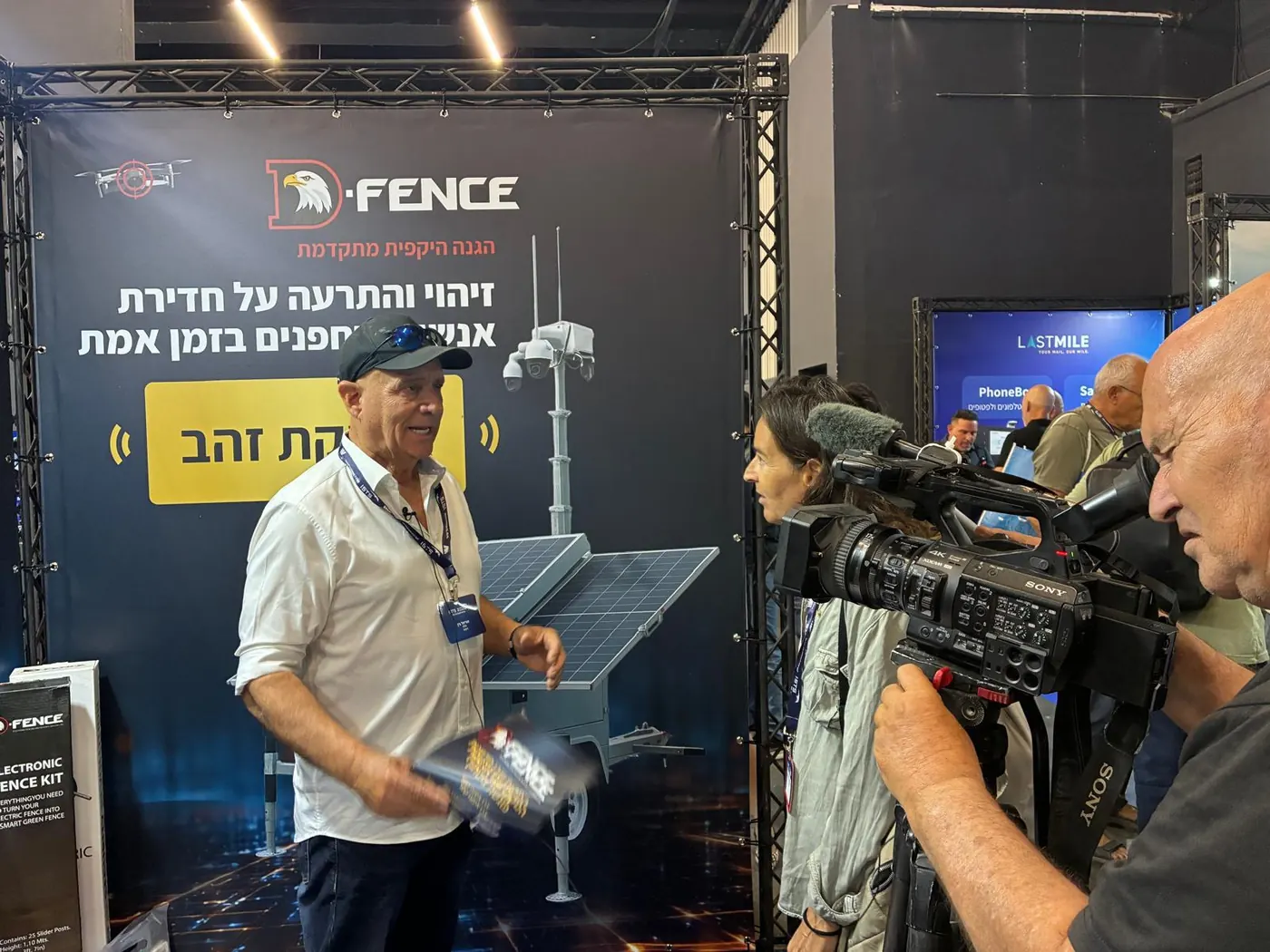 A television crew interviews D-FENCE at its stand at a defence exhibition