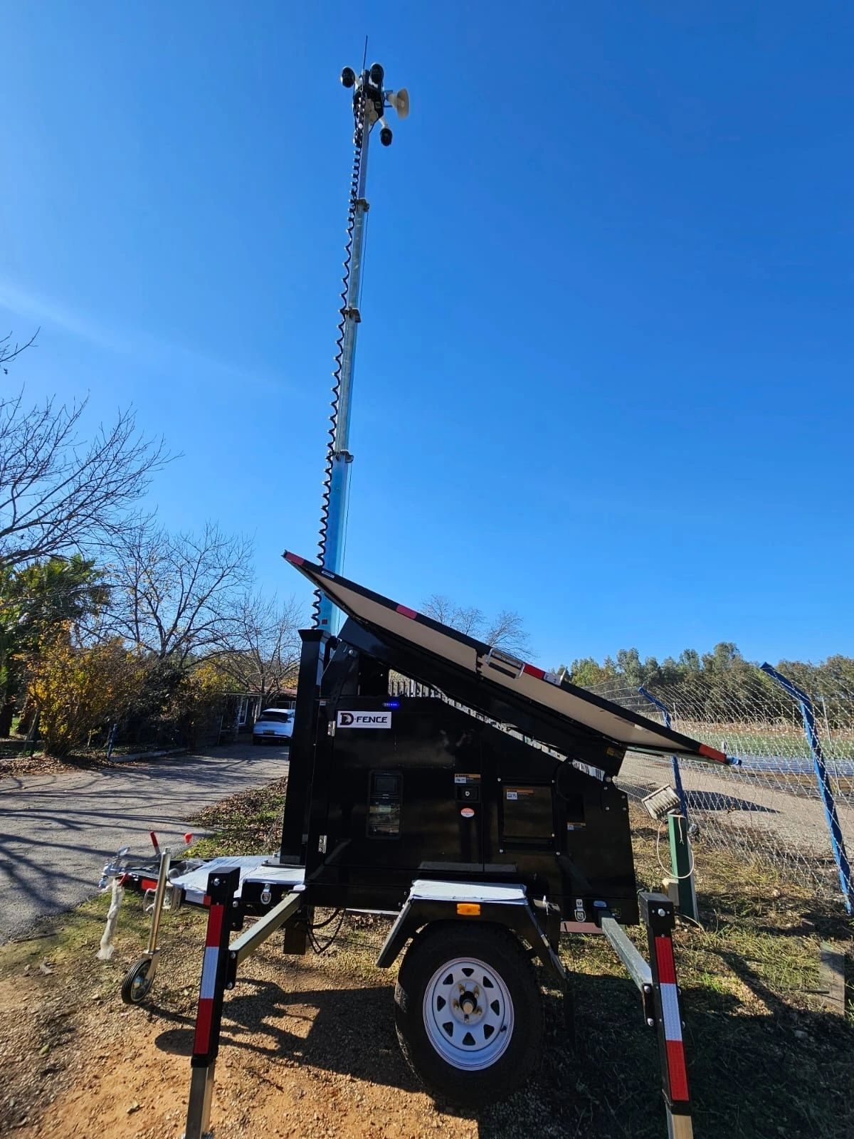 Black AI-EYE IN THE SKY trailer with its telescopic mast fully extended against a deep blue sky