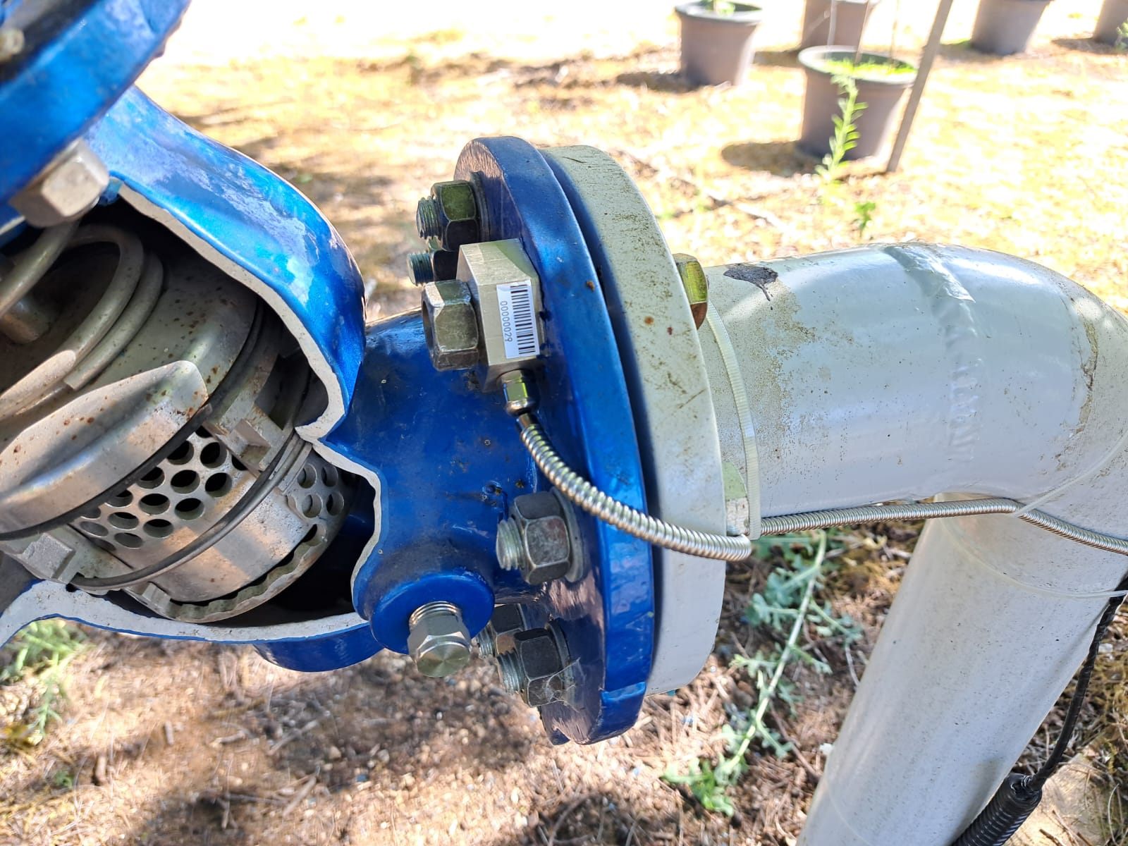 D-Bolt sensing nut with a serial label on the flange bolt of a blue water valve, armoured cable running to the control card