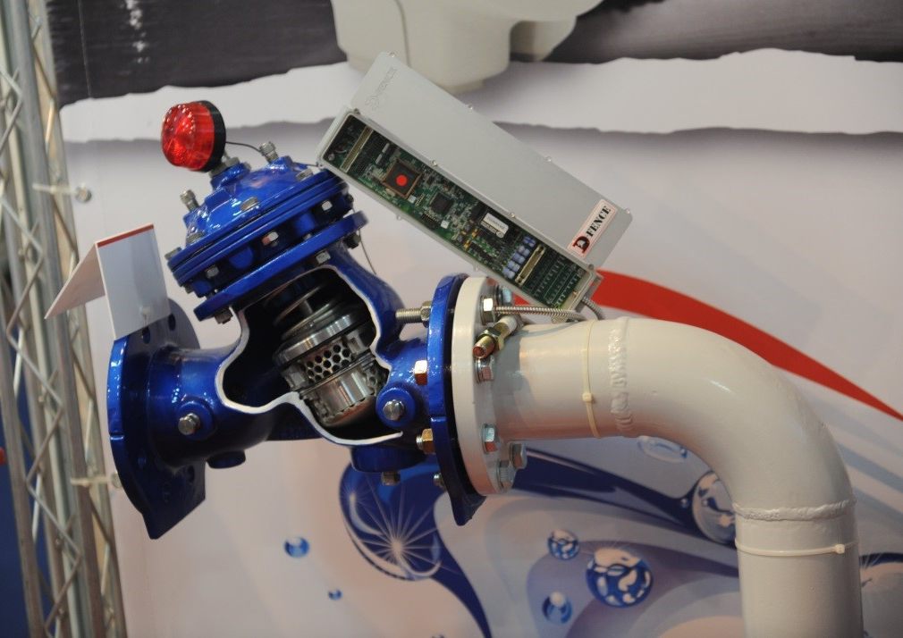 Cut-away blue valve on a white pipe fitted with a D-FENCE control card and a red local beacon, at an exhibition