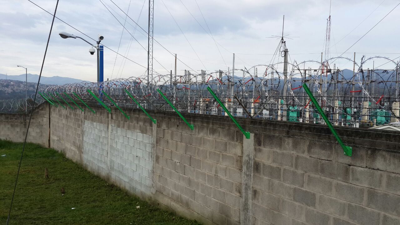 Concertina on green sensor arms along a block wall around an electrical installation