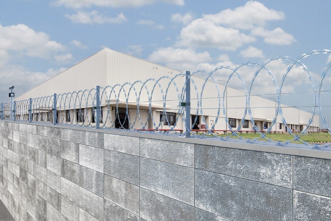 Concertina on sensor posts along the top of a clad wall around a logistics warehouse