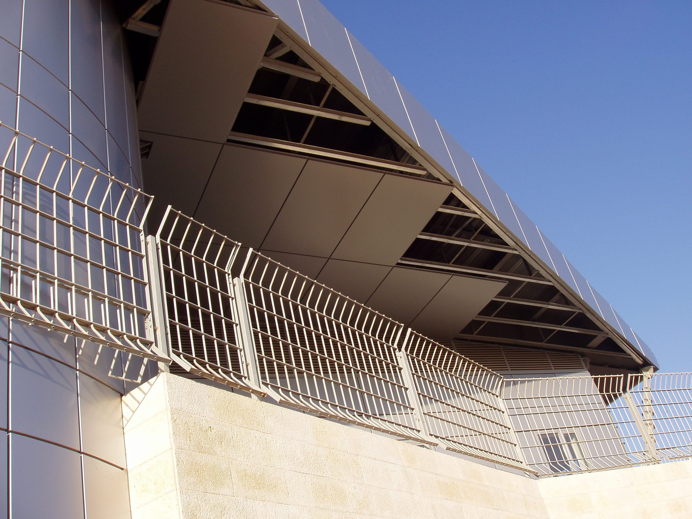 D-Corative fence mounted on top of an existing stone wall beside a terminal building at Ben Gurion Airport
