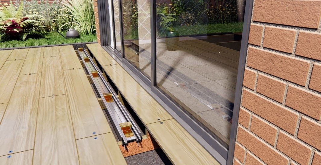 Timber decking along a sliding glass door with boards removed to show the sensor rails and brackets