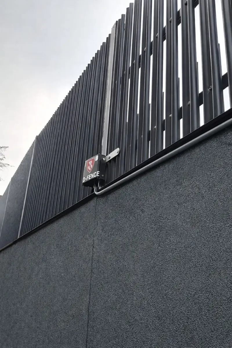 D-FENCE sensor unit and bracket on an architectural pale fence mounted above a wall