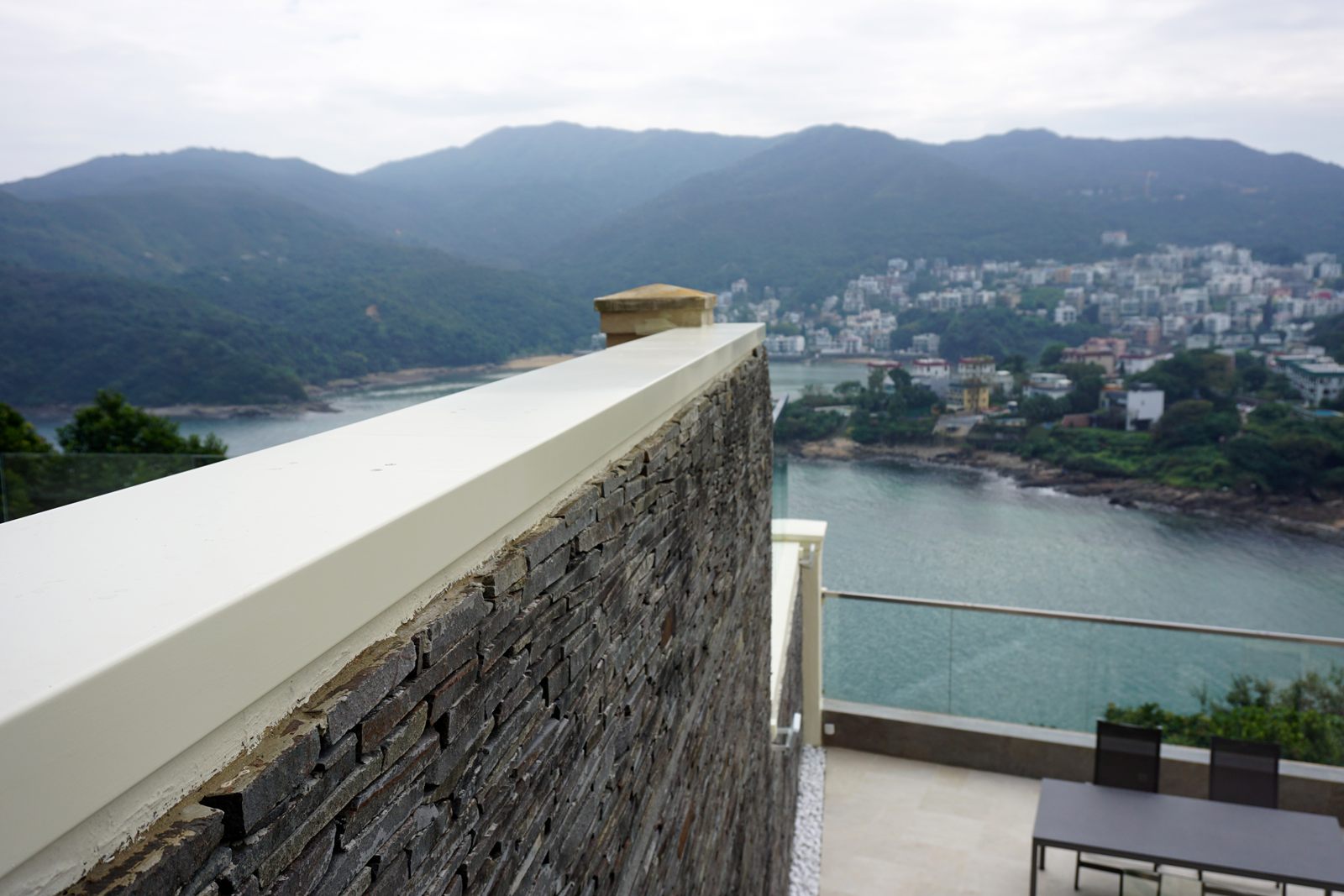 Stone-clad residential wall with a flush coping that hides D-Pressure Strip sensors, above a bay