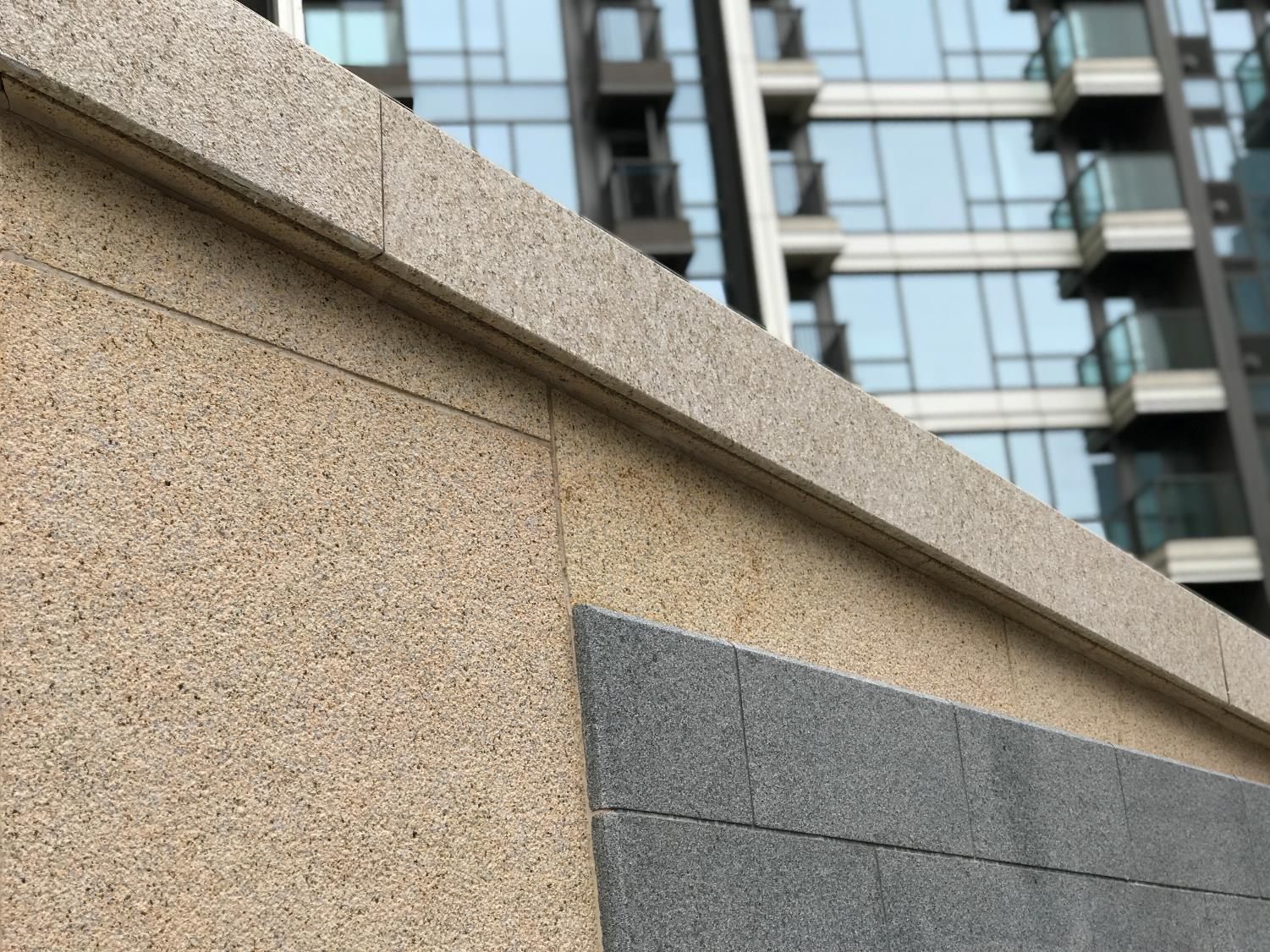Granite-clad perimeter wall with a stone coping below residential towers, protected by D-Tech