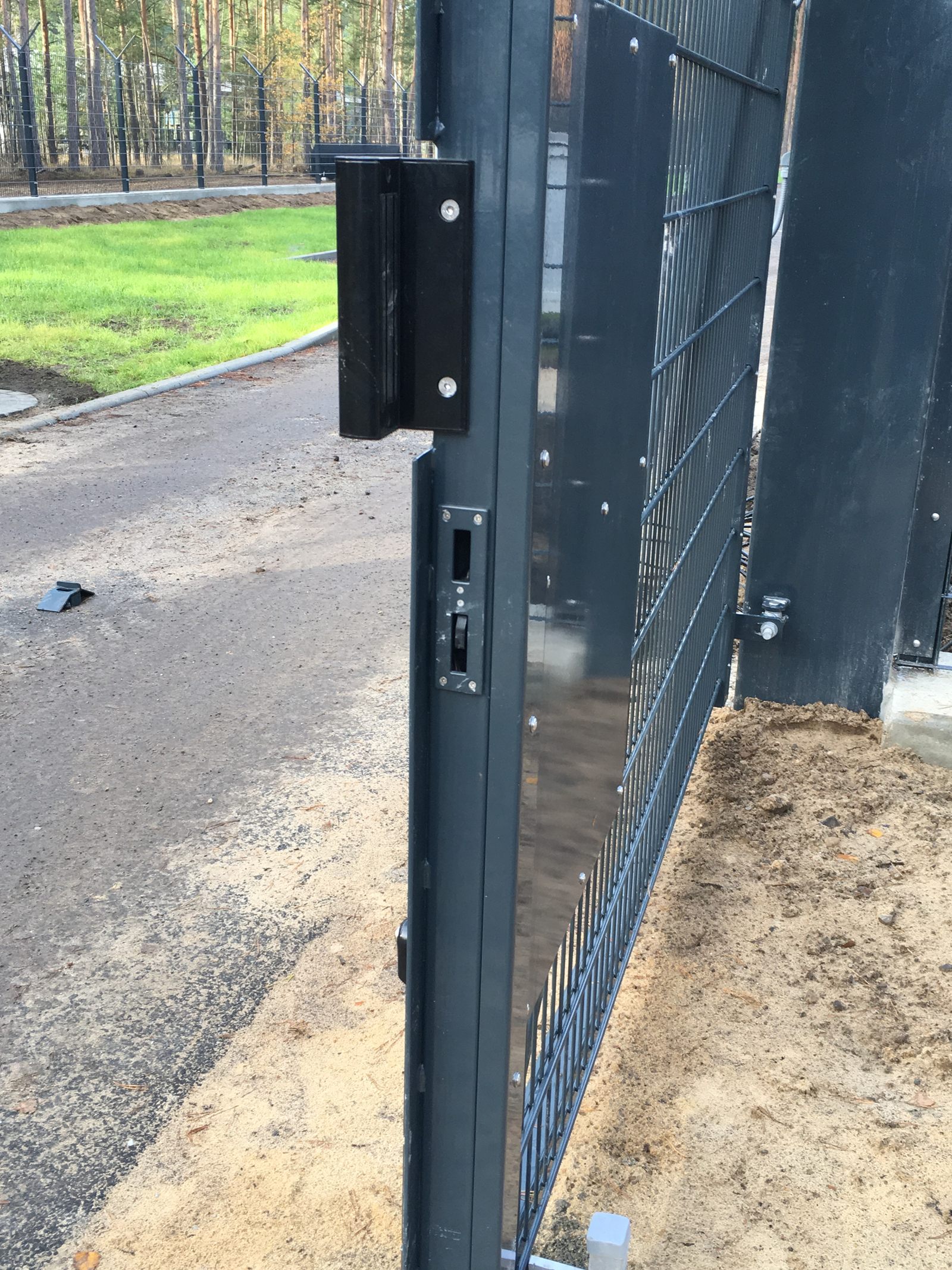 Close-up of a black sensor post holding welded-mesh panels, with the sensor housing visible